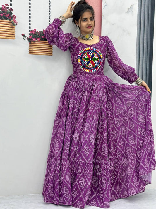 Woman wearing a purple traditional outfit with a colorful design, standing indoors.
