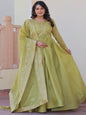 Woman wearing a green traditional outfit with embroidery indoors.