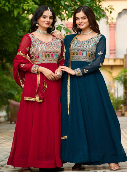 Two women in traditional outfits standing outdoors with greenery in the background