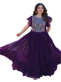 Woman in a purple traditional outfit with floral patterns standing outdoors.