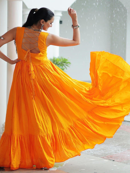 Woman in a bright yellow dress with a flowing skirt, standing in a sunlit outdoor setting.