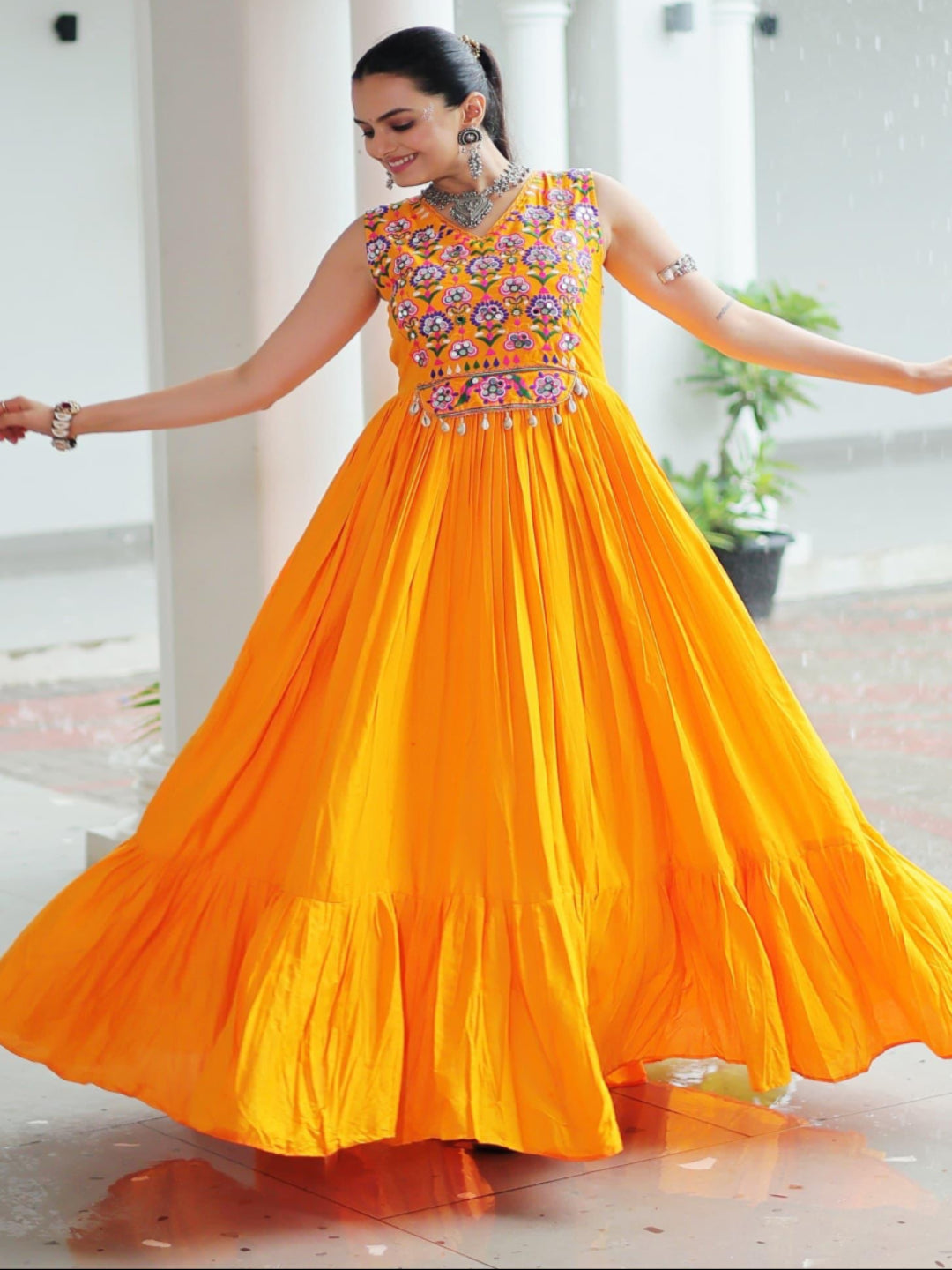 Woman in a bright orange dress with floral patterns in an indoor setting