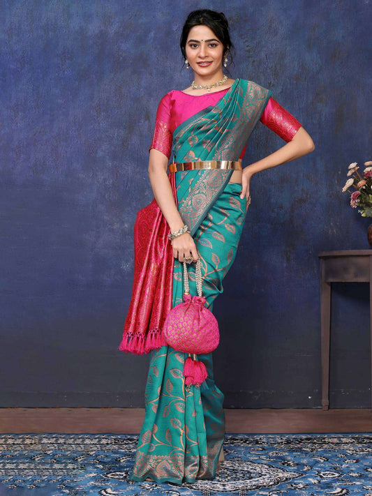 Woman wearing a green saree with pink blouse against a blue textured wall.