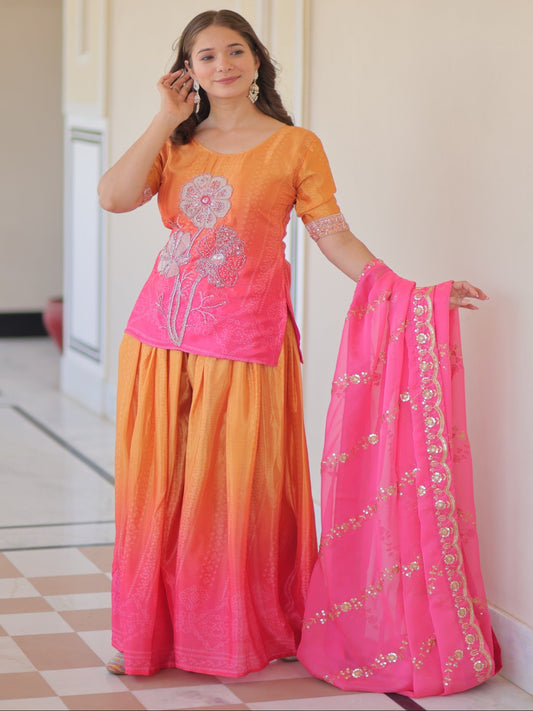 Woman wearing a traditional outfit with an orange and pink dress and matching dupatta.
