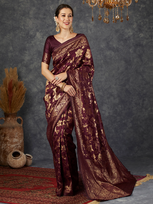 Woman wearing a maroon saree with gold patterns against a dark background