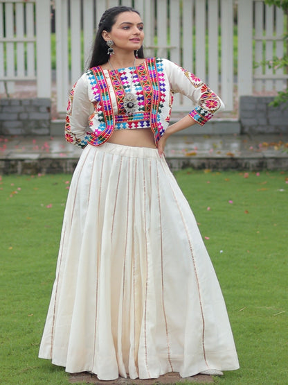 Woman in traditional outfit standing in a garden with floral arches.