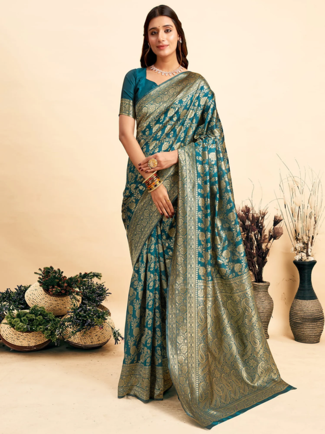 Woman wearing a green and blue saree with a neutral background