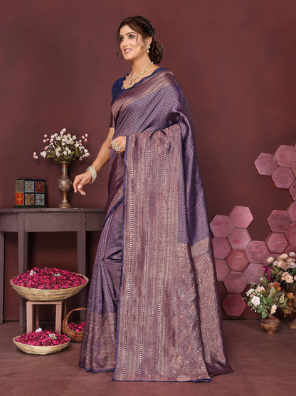 Woman in a purple saree standing in a decorated room with flowers and decor items.