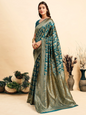Woman wearing a green and blue saree with a neutral background