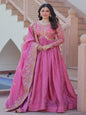 Woman in a pink traditional outfit standing in front of a staircase.