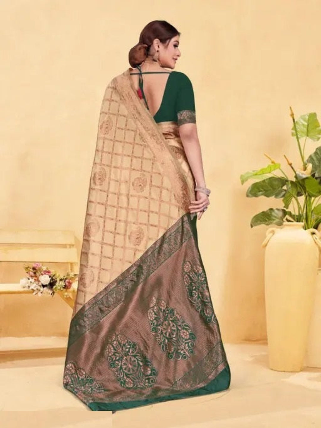 Woman wearing a saree with a green blouse against a beige background
