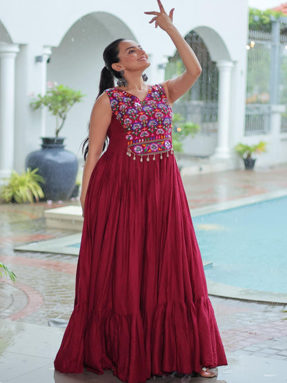 Woman in a red dress with floral patterns standing by a poolside.