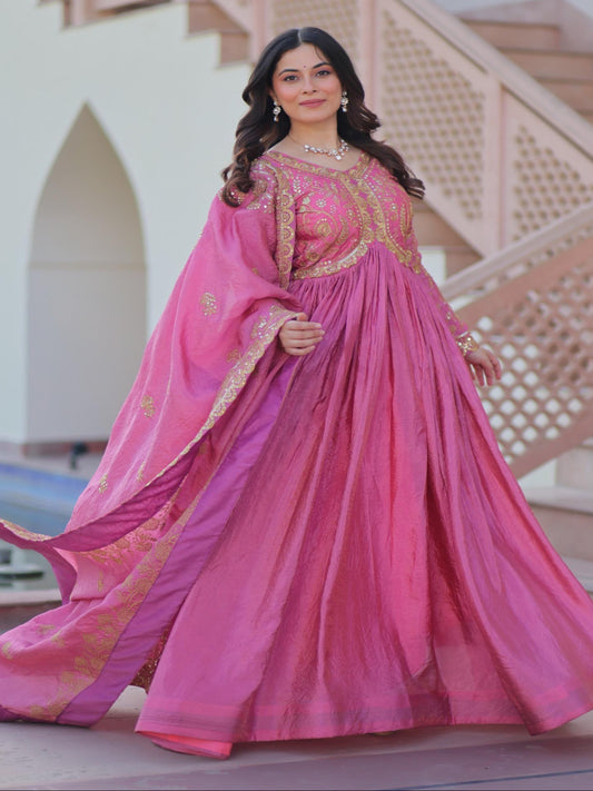 Woman in a pink traditional outfit standing in front of a decorative architectural background