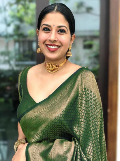 Woman wearing a green saree with gold jewelry indoors