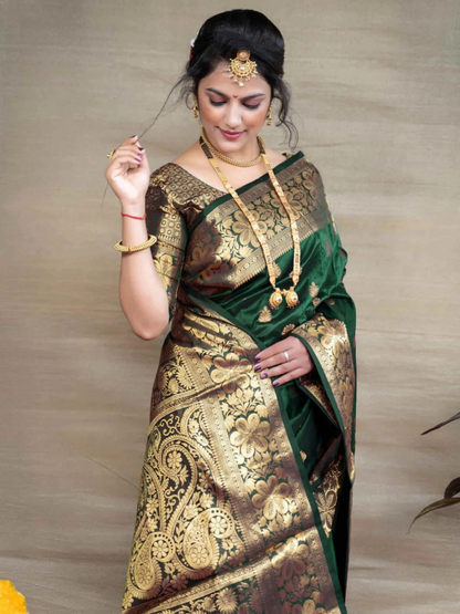Woman wearing a traditional green and gold saree with jewelry against a neutral background