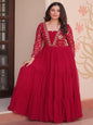 Woman wearing a red traditional outfit with intricate designs in a decorated room.