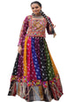 Woman in a colorful traditional outfit standing in front of a white building with arched windows.