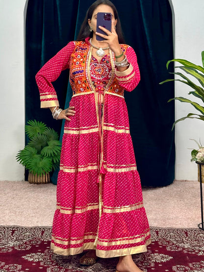 Person wearing a vibrant traditional outfit with a pink and orange patterned dress, standing in front of a mirror.