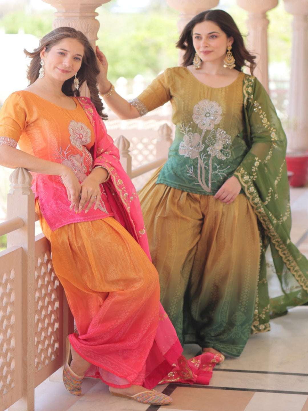 Two women in traditional Indian attire standing on a balcony.