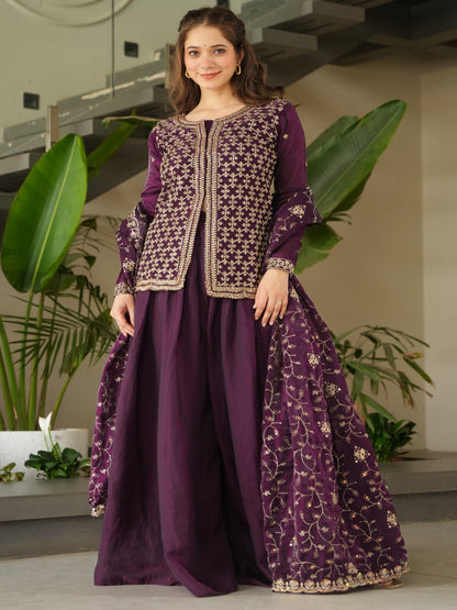Woman wearing a purple embroidered outfit in an indoor setting with plants.
