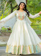 Woman in a white traditional outfit with colorful embroidery standing outdoors.