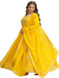 Woman in a yellow traditional outfit standing by a pool with greenery in the background