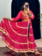 Person wearing a traditional outfit with a pink saree and orange blouse, standing in front of a mirror.